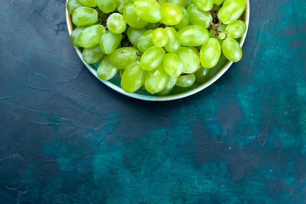 Free photo top view fresh green grapes mellow and juicy fruits inside plate on the dark blue desk.