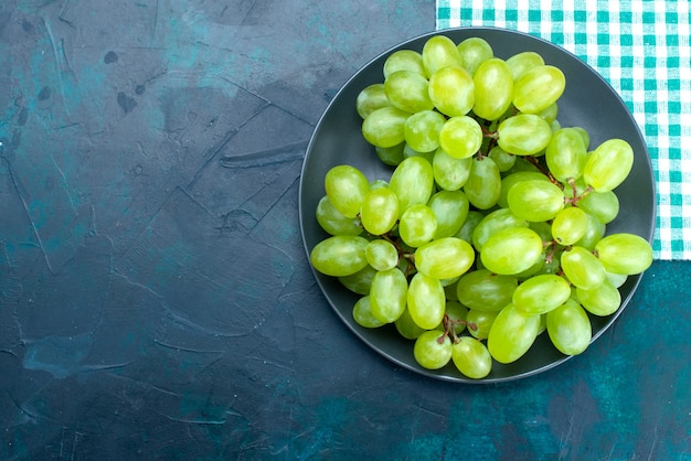 Top view fresh green grapes mellow juicy fruits inside plate on the dark-blue desk.