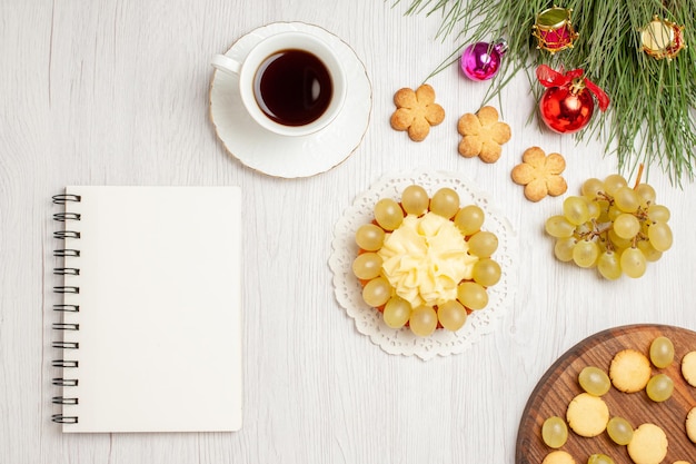 Top view fresh green grapes with cup of tea and cake on white desk fruit mellow juice color raisin