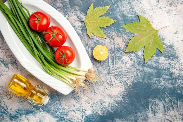 Top view fresh green onion with tomatoes on the light-blue background