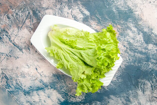 Top view fresh green salad inside plate on light-blue background