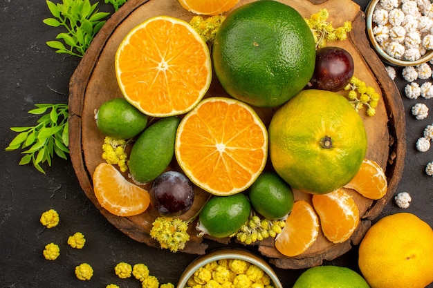 Top view of fresh green tangerines with feijoas and candies on dark