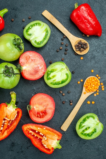 Free photo top view fresh green tomatoes red bell peppers cozy red lentils and black pepper on dark background