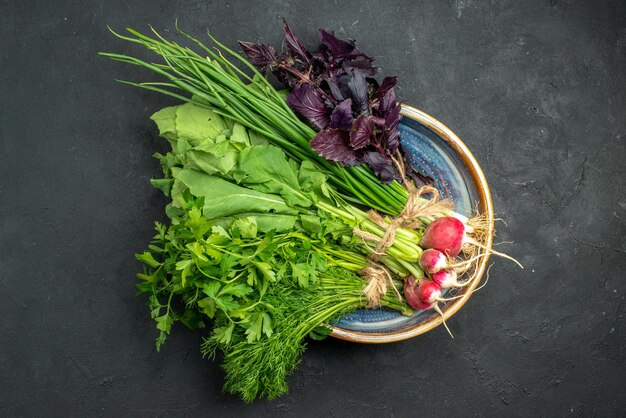 Top view fresh greens with radish on dark background