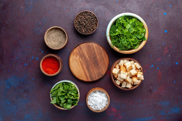 Top view fresh greens with rusks and seasonings on the dark table, meal soup green food