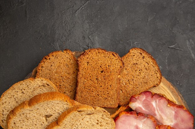 Top view fresh ham slices with buns and bread slices on dark background