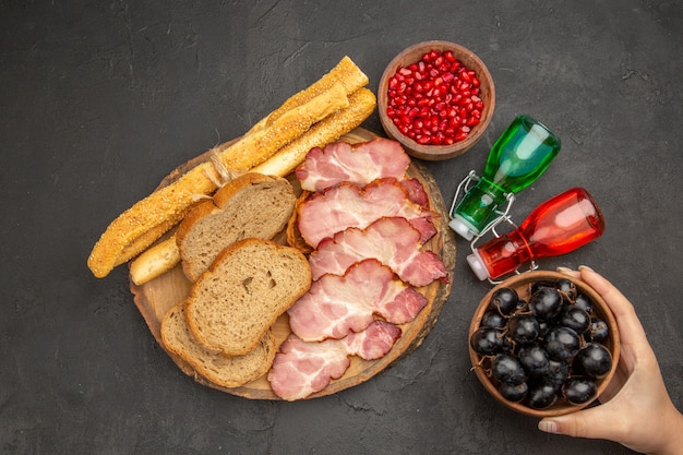 Top view fresh ham slices with fruits bread and buns on dark background