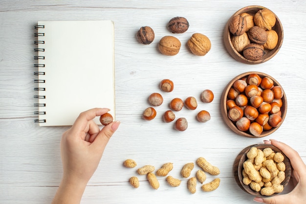 Top view fresh hazelnuts with peanuts and walnuts on white table