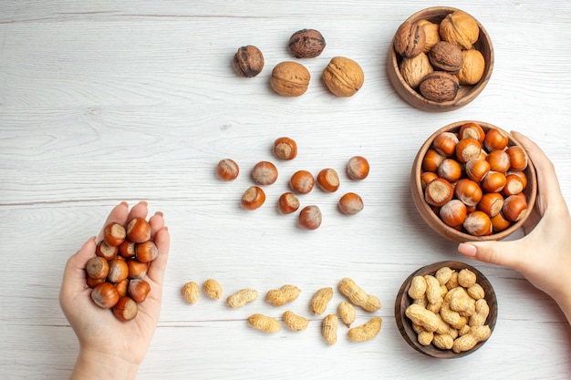 Top view fresh hazelnuts with peanuts and walnuts on white table