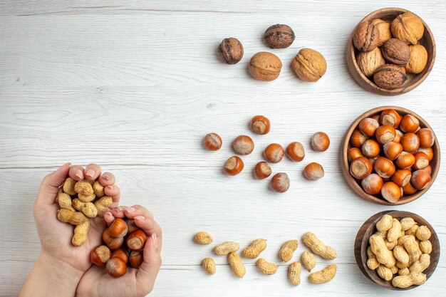 Top view fresh hazelnuts with peanuts and walnuts on white table