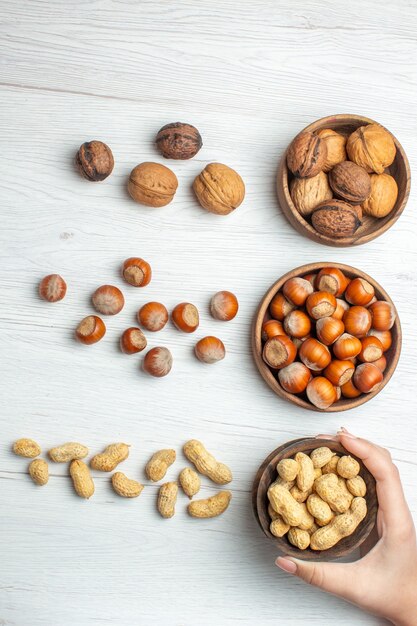 Top view fresh hazelnuts with peanuts and walnuts on white table