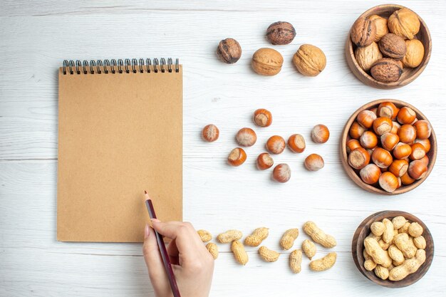 Top view fresh hazelnuts with peanuts and walnuts on white table