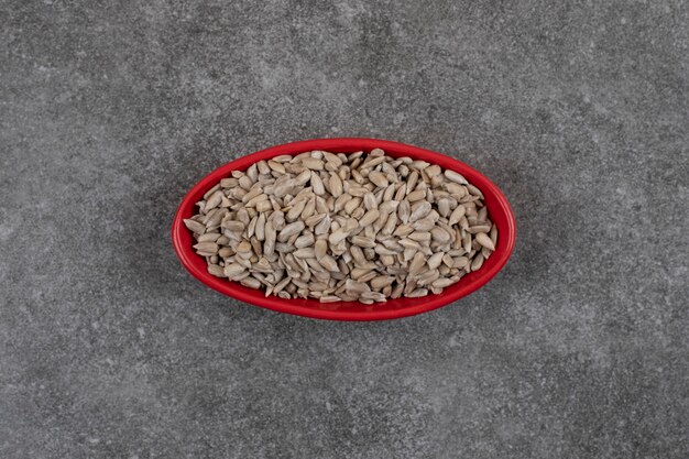 Top view of fresh healthy sunflower seeds in red bowl.