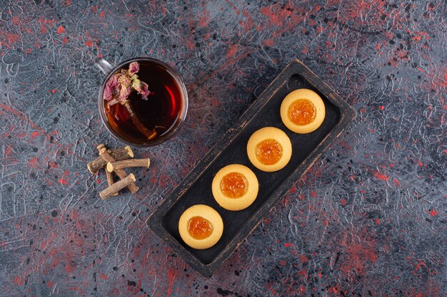 Top view of fresh jam cookies with fragrant tea on rustic.