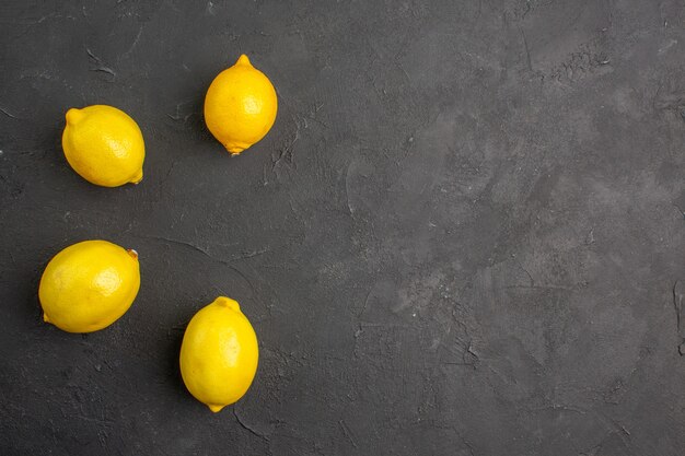 Top view fresh lemons lined on a dark table citrus yellow fruit free space for text