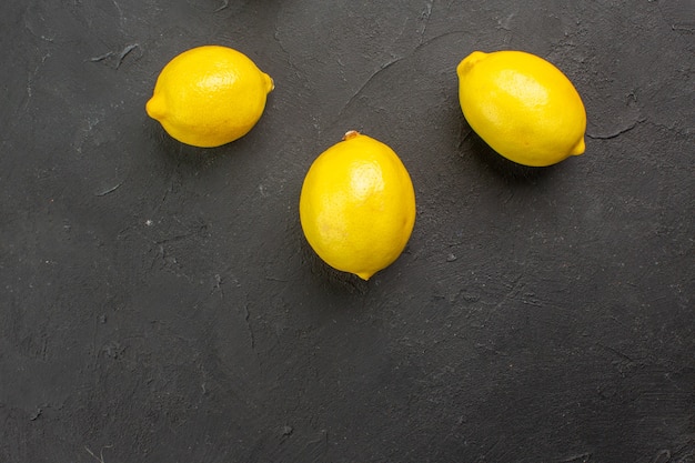 Top view fresh lemons lined on dark table citrus yellow fruit lime