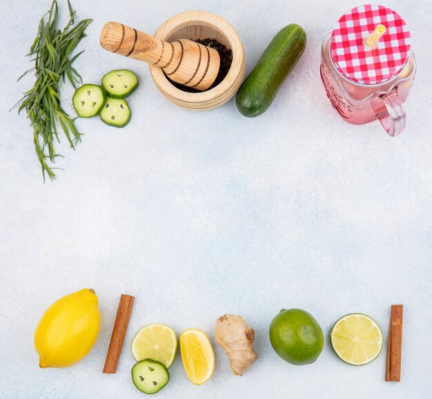 Top view of fresh lemons with cinnamon sticks cucumber and tarragon greens on white with copy space