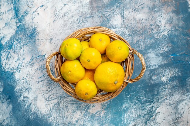 Free Photo top view fresh mandarins on wicker basket on blue white surface copy space