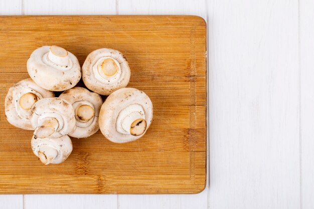 Top view of fresh mushrooms champignon on wooden board on white background