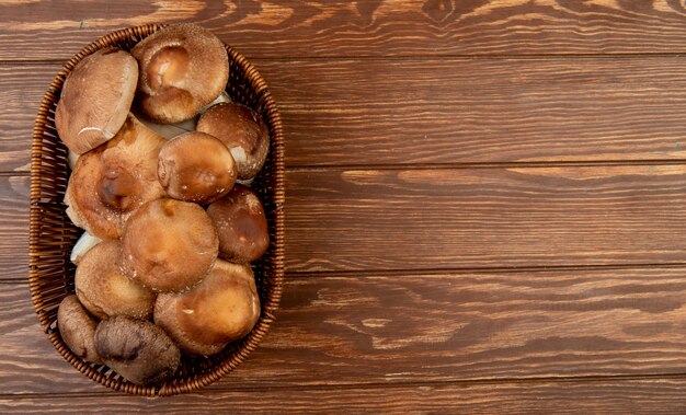 Top view of fresh mushrooms in a wicker basket on wood rustic with copy space