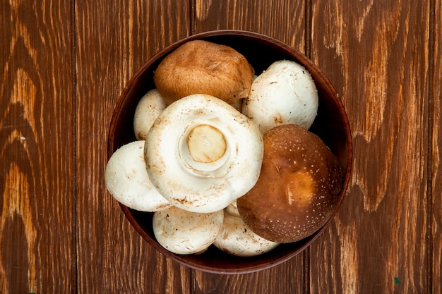 top view of fresh mushrooms in a wooden bowl on rustic surface