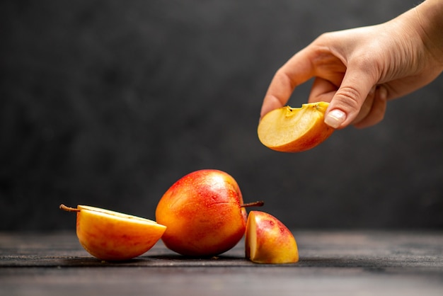 Top view of fresh natural chopped and whole red apples hand taking one of limes on black background