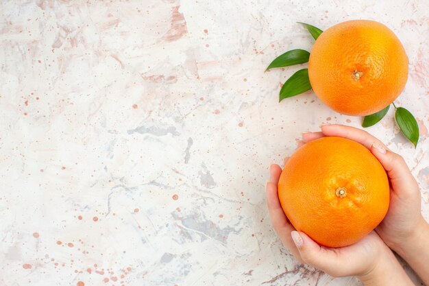 Top view fresh oranges in female hand and on bright isolated surface with copy space