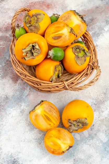 Free photo top view fresh persimmons feykhoas in wicker basket on nude background