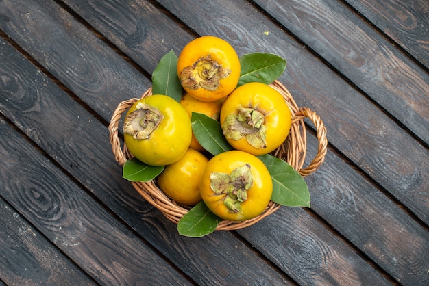 Free photo top view fresh persimmons ripe sweet fruits on wooden rustic table, fruit mellow