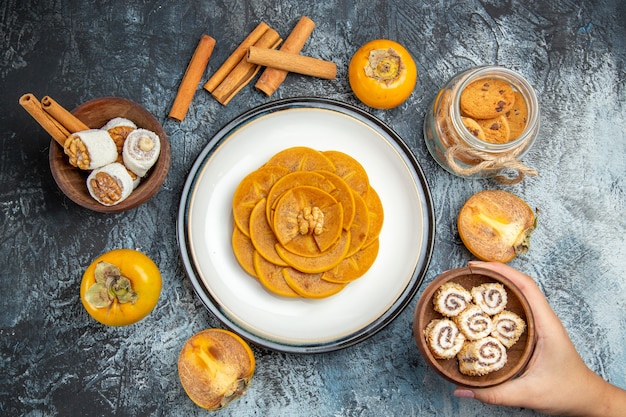 Free photo top view of fresh persimmons with confitures and cinnamon on dark surface