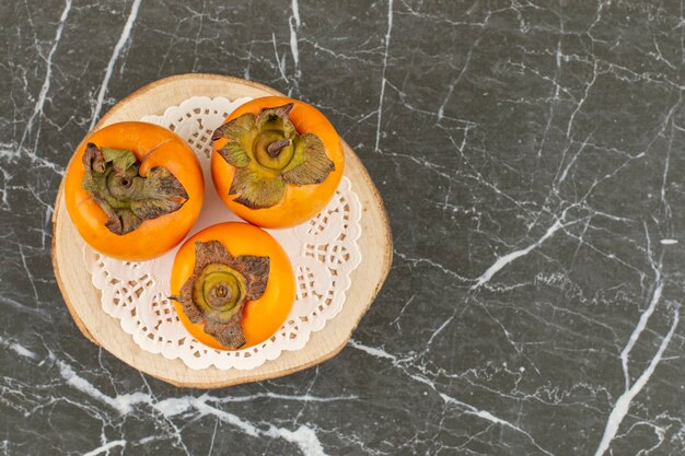 Free Photo top view of fresh persimmons on wooden board.