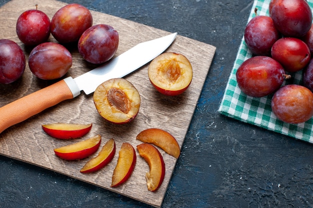 Top view of fresh plums whole mellow and juicy sliced on dark-grey desk, fruit fresh vitamine summer