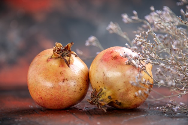 Free Photo top view fresh pomegranates dried wild flower branch on dark red isolated background