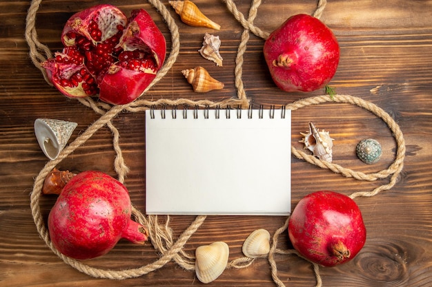 Top view fresh pomegranates with ropes on brown desk