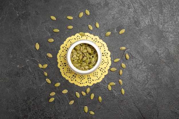 Free photo top view fresh pumpkin seeds on dark background seed color many pumpkin granule