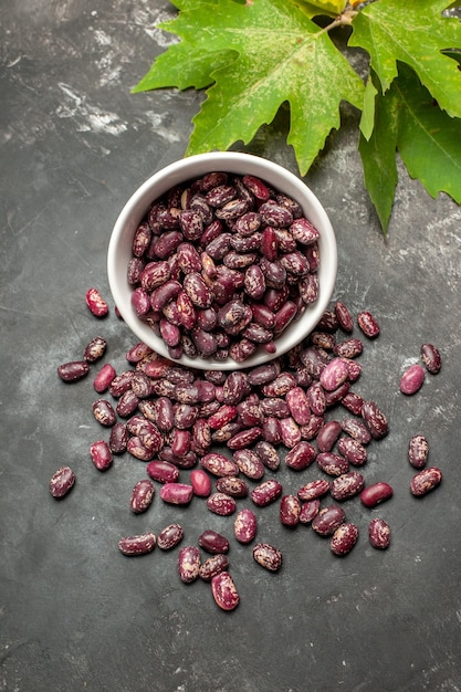 Free photo top view fresh raw beans with green leaves on grey surface