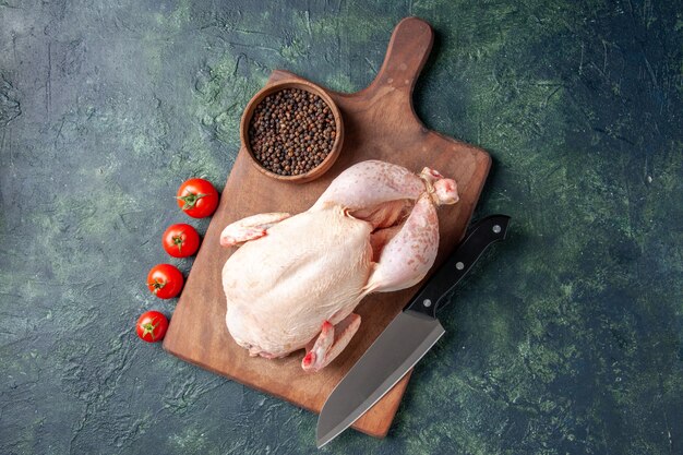 Top view fresh raw chicken with red tomatoes on a dark-blue background kitchen meal animal photo food chicken meat color farm