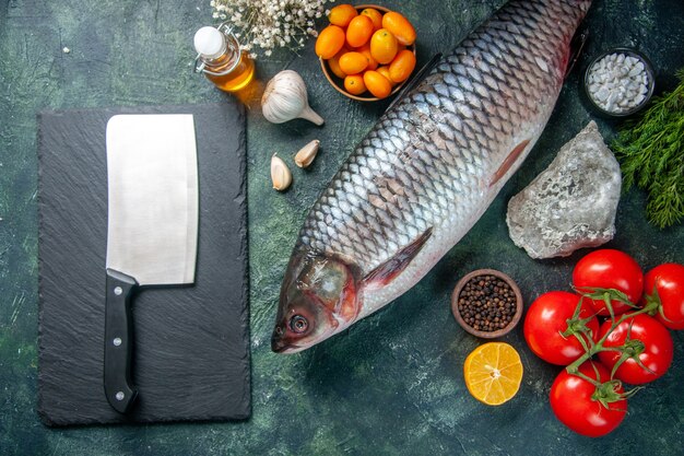 top view fresh raw fish with red tomatoes on dark background