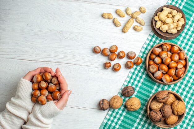 Top view fresh raw hazelnuts with peanuts and walnuts on white table