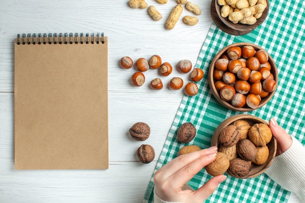 Free photo top view fresh raw hazelnuts with peanuts and walnuts on white table