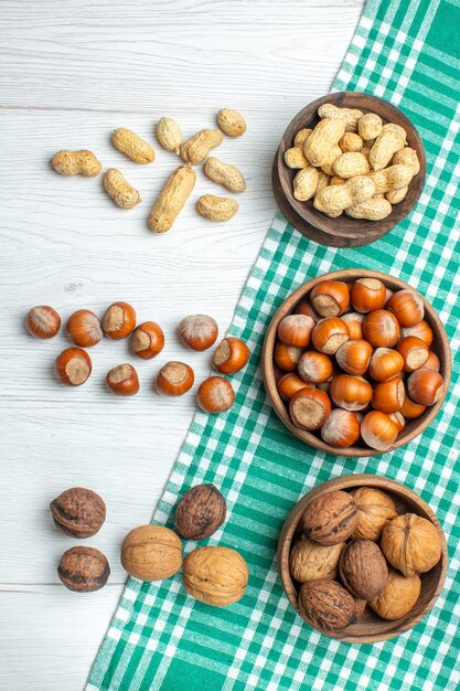 Top view fresh raw hazelnuts with peanuts on white table