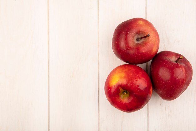 Top view of fresh red apples isolated on a white wooden surface with copy space