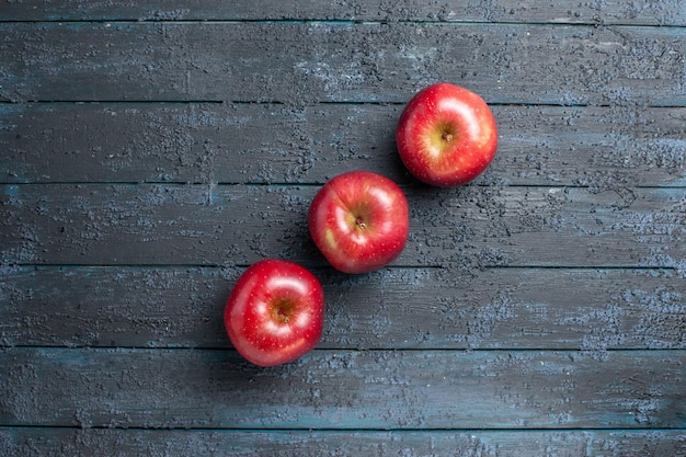 Free photo top view fresh red apples ripe and mellow fruits lined on dark-blue desk many fruits red fresh plant color tree