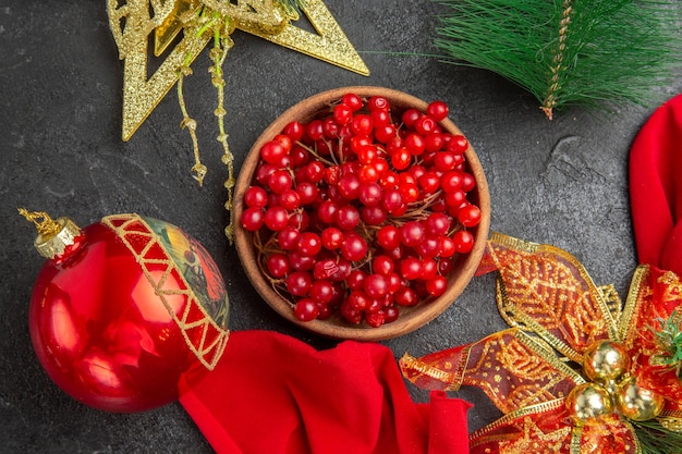 Top view fresh red cranberries around christmas toys on a dark background