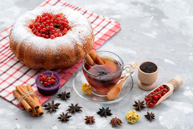 A top view fresh red cranberries sour and mellow with round cake tea and cinnamon on the white desk fresh color