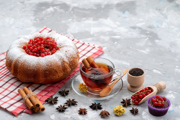 A top view fresh red cranberries sour and mellow with round cake tea and cinnamon on the white desk fruit berry