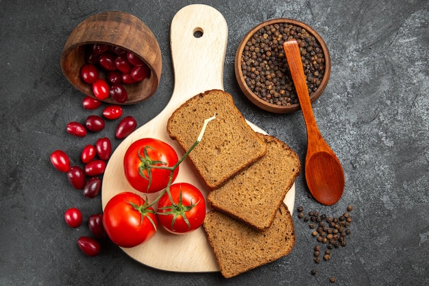 Free Photo top view of fresh red dogwoods with bread loafs and tomatoes on grey surface