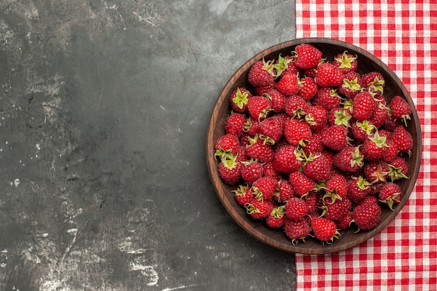 Free photo top view fresh red raspberries inside plate on grey background