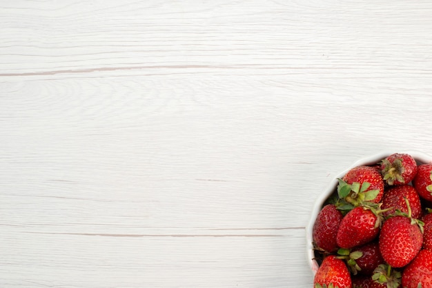 Free photo top view of fresh red strawberries mellow and delicious berries inside white plate on light, fruit berry fresh red