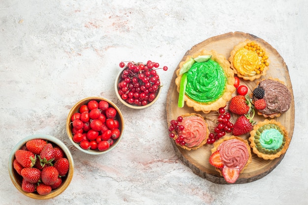 Top view fresh red strawberries with fruits and cakes on white table fruit berry